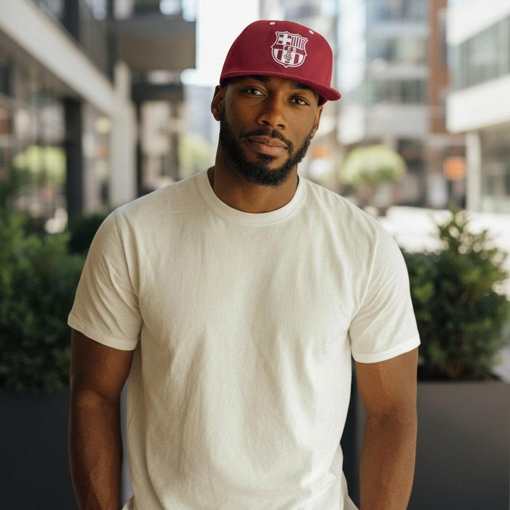 Man wearing a maroon Barcelona Cap Bankroll Snapback Hat with white logo and a plain white t-shirt in an urban setting.
