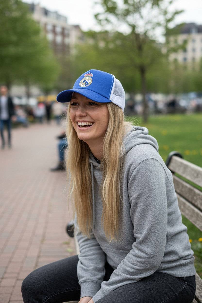 Woman wearing Fan Ink officially licensed trucker hat with embroidered soccer crest and mesh back outdoors sitting on bench