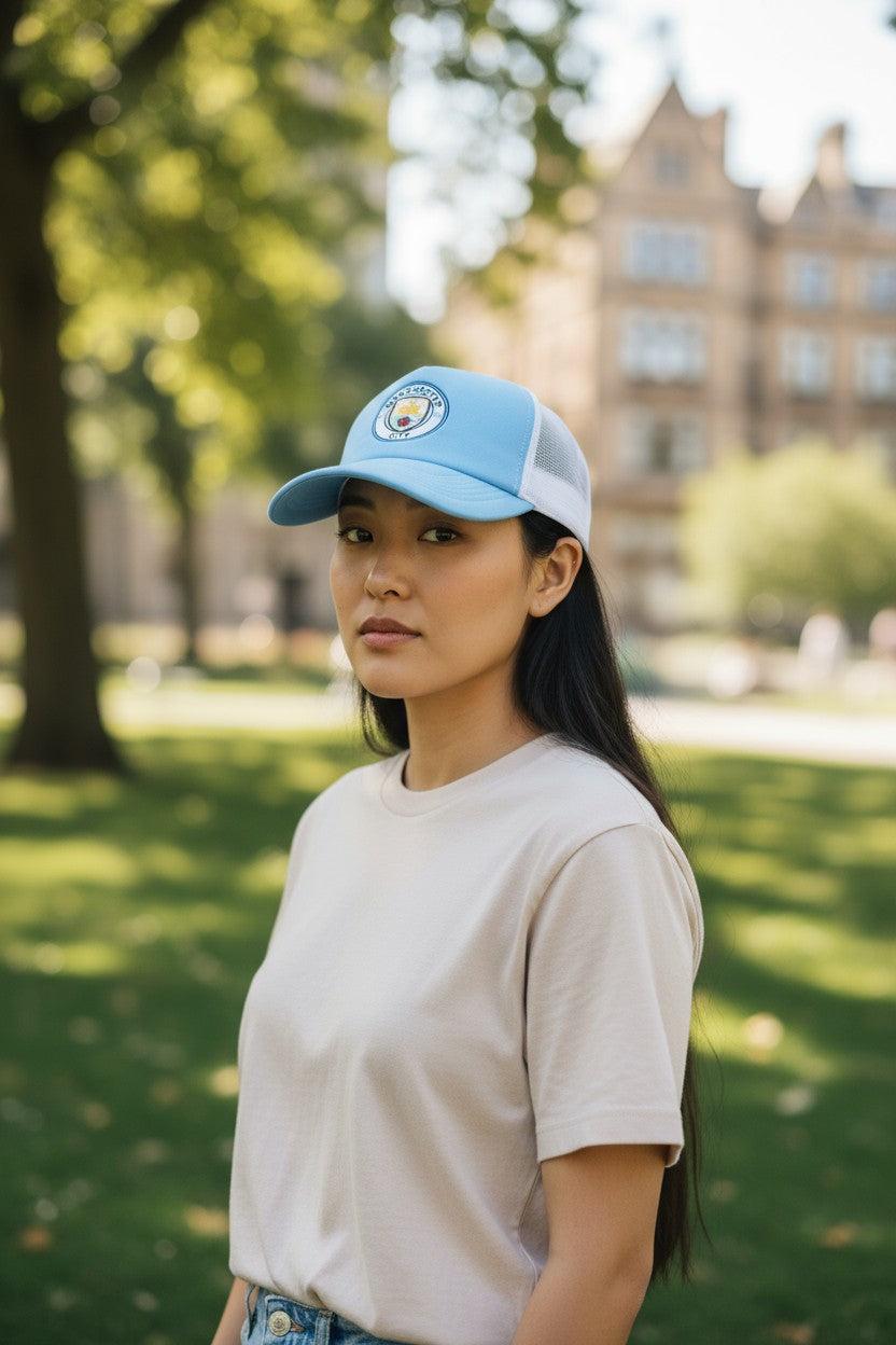 Woman wearing a light blue Fan Ink officially licensed soccer trucker hat with embroidered crest and mesh back in outdoor park setting