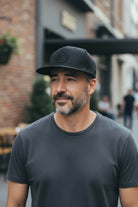 Man wearing black Fan Ink Dawn fitted hat showing team style outdoors