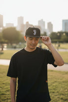 Man wearing black Fan Ink officially licensed Juventus snapback hat with flat bill and embroidered team logo outdoors