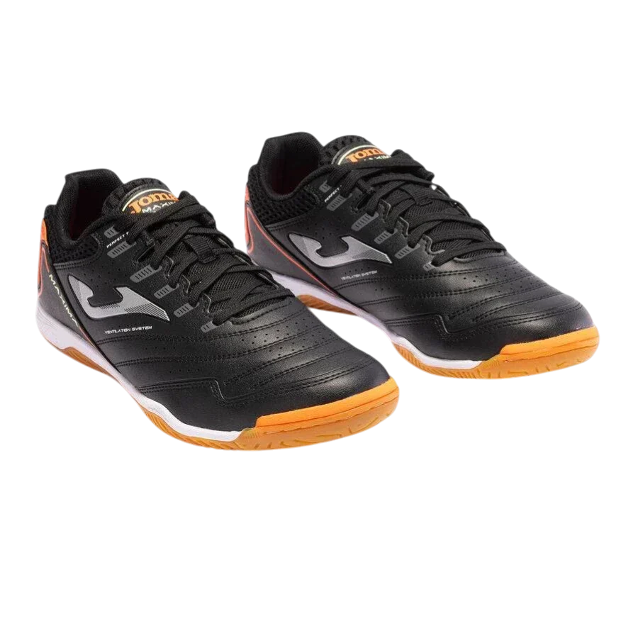 Joma Maxima indoor soccer shoes in black synthetic material, with textured panels, white logos and orange rubber soles