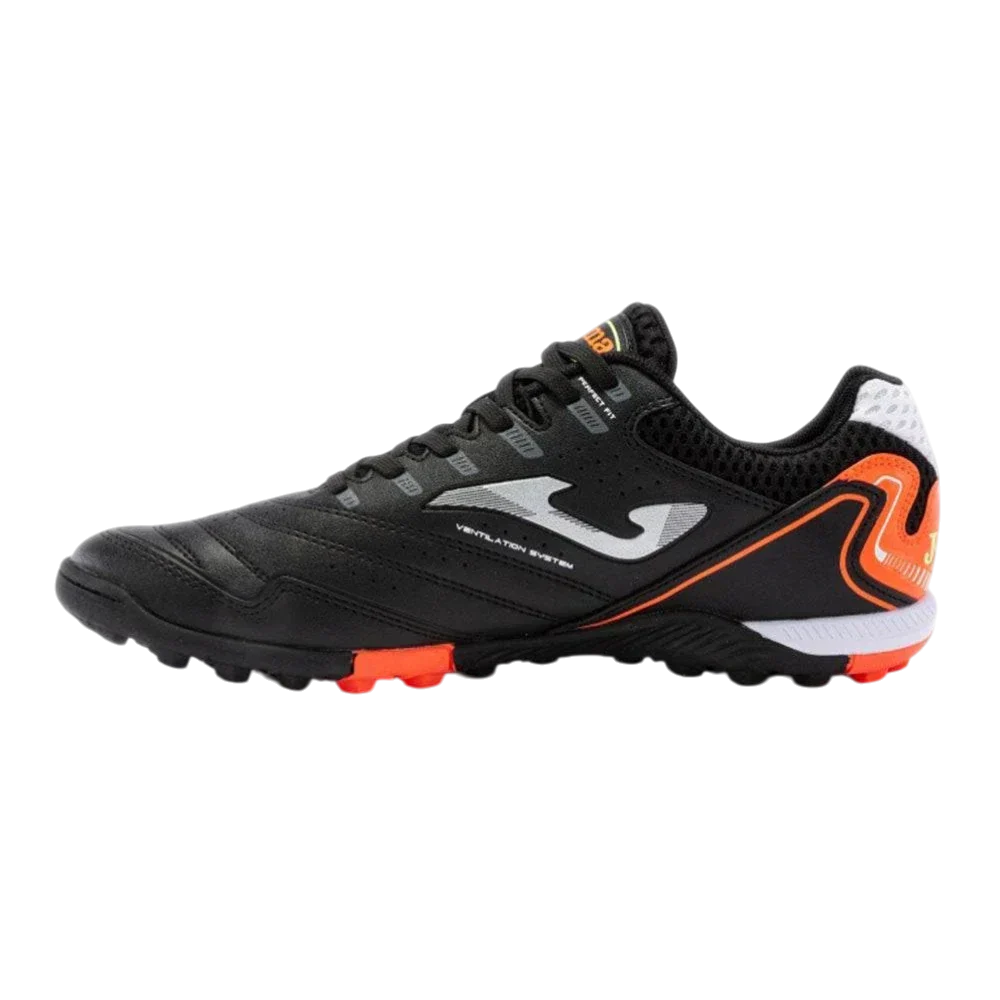 Joma Maxima turf soccer shoe in black synthetic material with orange accents, a white logo and rubber turf studs